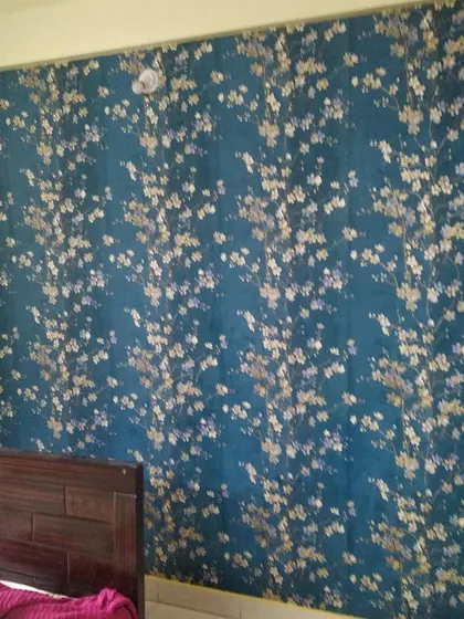 A dark teal wallpaper with a delicate gold floral pattern installed in a bedroom. This design creates a moody and luxurious atmosphere.