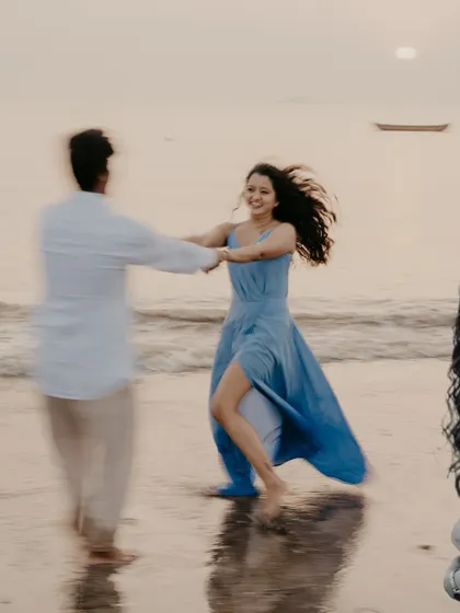 A joyful, motion-filled photo of the couple dancing on the sand at sunset, capturing pure happiness.