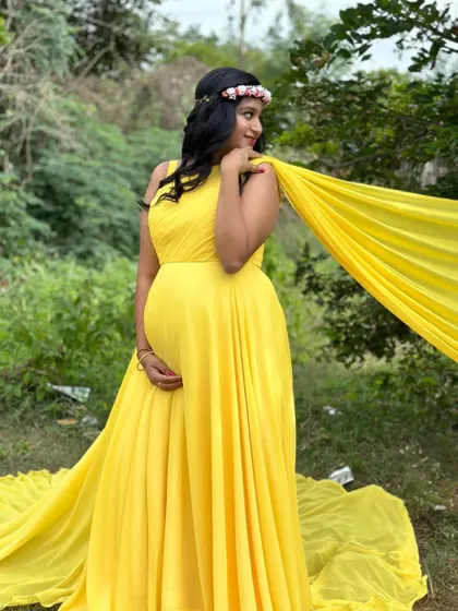 The long yellow trail of this maternity gown looks incredible as it flows behind the mother-to-be.