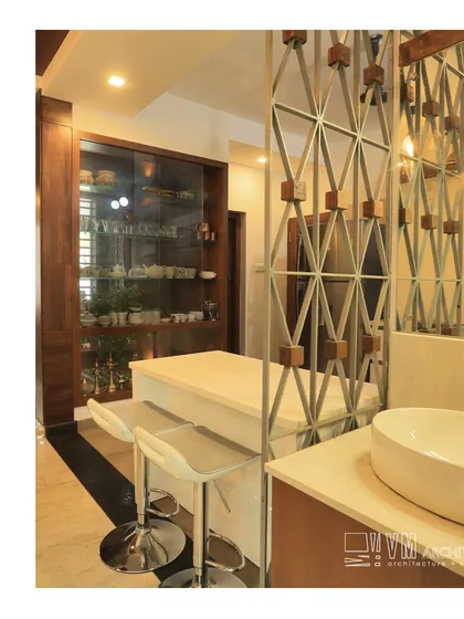 A modern breakfast bar and wash area in the Thalassery residence, separated by a custom metal and wood partition that adds an artistic touch.