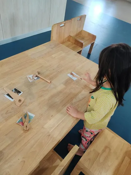 This child stands at the table to match the toy tools to the correct cards. This reinforces vocabulary and understanding of how different tools work.