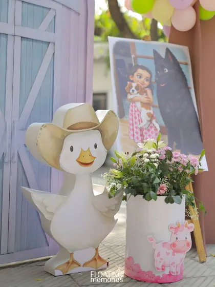 Personal touches are key. We incorporated a beautiful portrait of the birthday girl with her pets, displayed alongside our custom themed decor like this cowboy duck and floral arrangement.