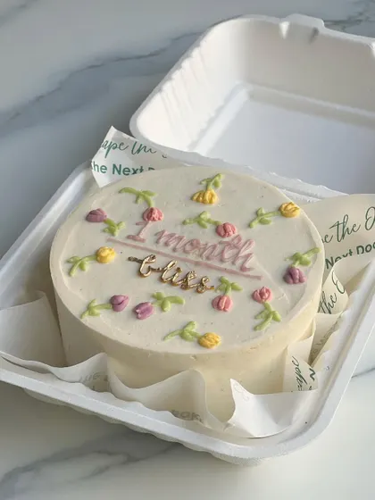 A sweet and delicate mini cake to celebrate a one-month milestone. The cake is decorated with tiny, hand-piped tulips in soft pastel colors.