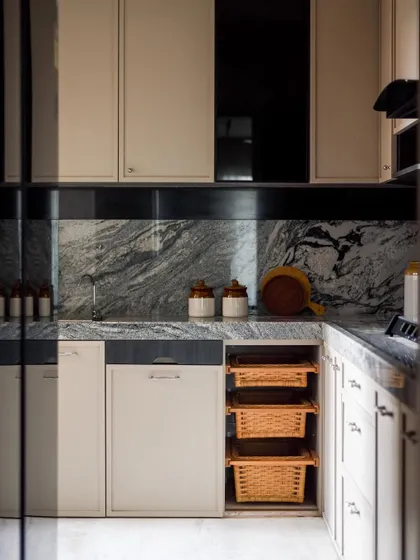 The kitchen is separated from the living area by a grey-tinted glass partition, creating a sense of privacy while maintaining a visual connection.