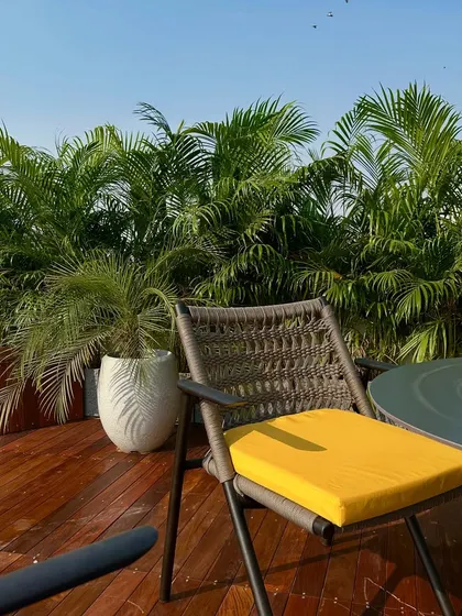 A detail shot of the outdoor dining chair with its bright yellow cushion, adding a pop of color to the otherwise neutral and green palette.