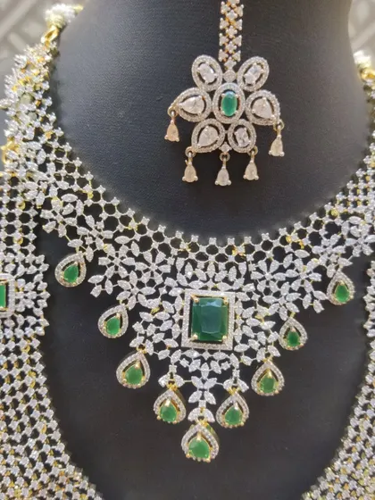 A detailed shot of the maang tikka and necklace from the American diamond and emerald set.