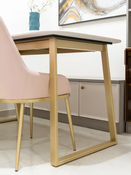 A close-up of the elegant dining chairs with blush pink upholstery and brushed gold legs, adding a soft, luxurious touch to the dining space.
