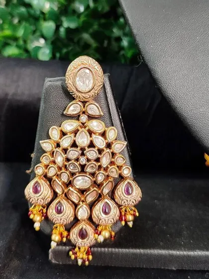 A beautiful chandelier earring with kundan work and ruby-colored drops. This rental piece is perfect for a glamorous evening look.