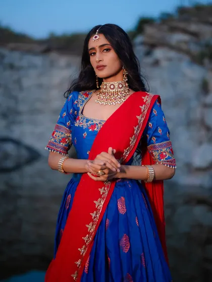 A royal blue half saree with a traditional Banarasi silk lehenga, paired with a hand-embroidered blouse and a contrasting red dupatta.
