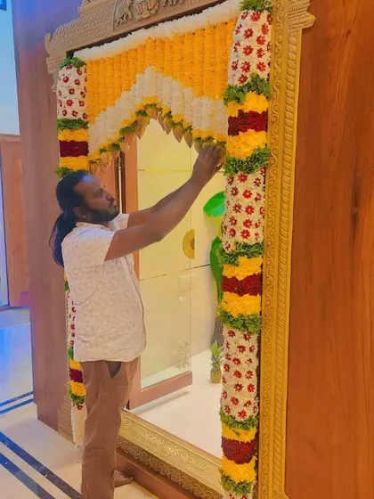 Adjusting the flower garlands on a pooja room door. Every element must be perfectly placed to create a harmonious and beautiful design.