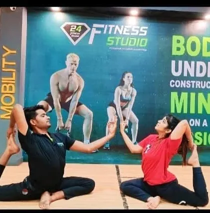 Partner yoga in a group setting. Here, two students work together in a variation of King Pigeon Pose, helping each other to achieve a deeper stretch and better alignment.