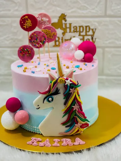 A magical unicorn cake with a rainbow mane and a golden horn. This enchanting design is decorated with colorful lollipops and spheres, perfect for a fairytale birthday.