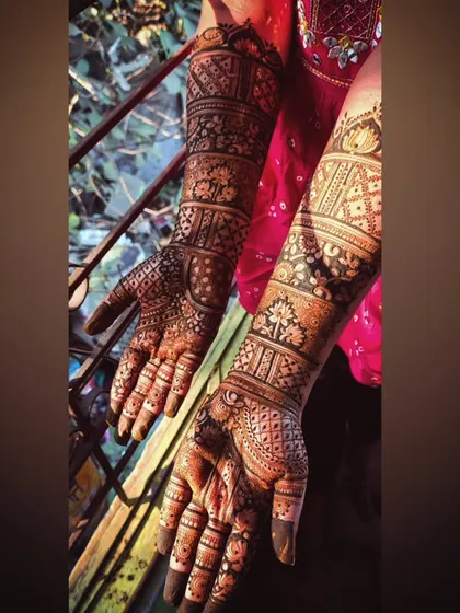 A full bridal mehendi for the bride Pooja, seen from a different angle. The design covers the hands and extends well up the arms for a complete bridal look.