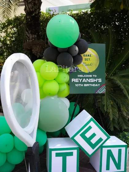 A fun decor piece with a giant tennis racket prop and letter blocks spelling 'TEN' for the 10th birthday.