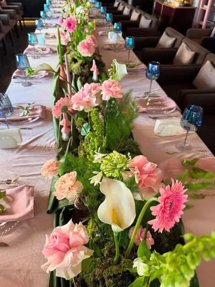 A close-up of the stunning floral table runner, showing the variety of pink and white flowers like carnations, gerberas, and calla lilies.