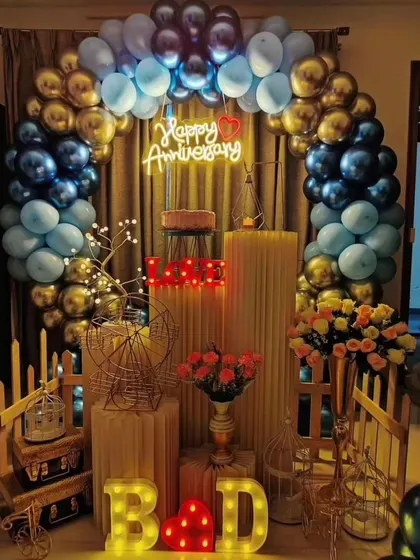 A beautiful anniversary decoration for a celebration at home. The blue and gold balloon arch, combined with a 'Happy Anniversary' neon sign and romantic props, creates a lovely setting.