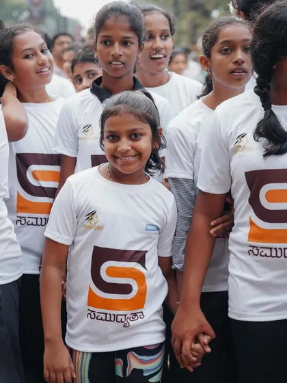 A group of girls holding hands and smiling, showcasing the friendships built through community events.