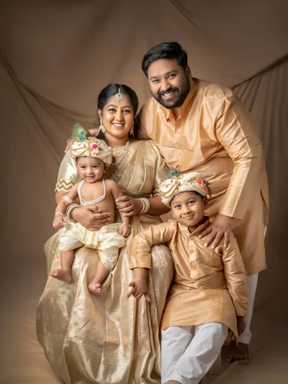 A stunning family portrait in traditional attire celebrating the Kannaiah theme. The coordinated golden outfits and the happy expressions make this a regal and heartwarming photograph.
