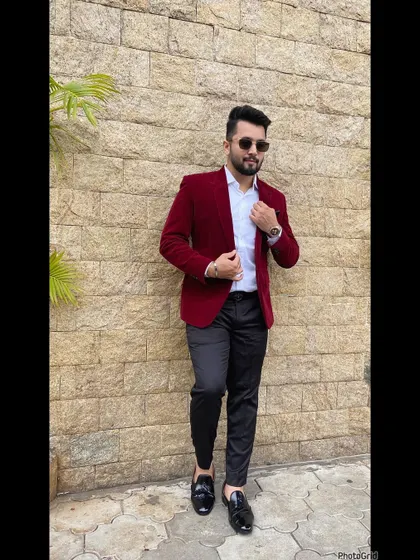 A full-length shot of my red velvet blazer outfit against a stone wall.
