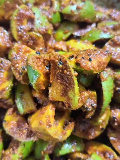A close-up of the mango pieces being tossed in spices. You can see the texture of the masala and the freshness of the mango.
