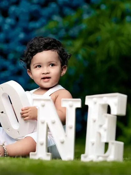 A first birthday celebration in the garden with a simple and elegant setup, featuring a 'ONE' sign against a beautiful floral background.