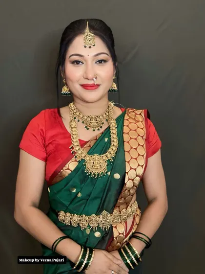 A closer look at this traditional ensemble. The makeup focuses on radiant skin and a bold red lip, perfectly matching the green saree with its red and gold border.