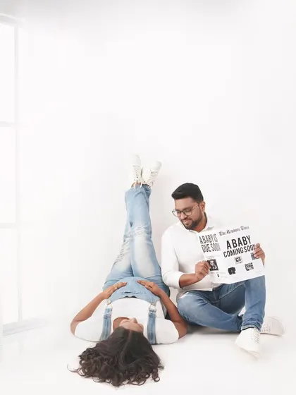 A playful pose for a pregnancy announcement. Using a custom sign adds a personal touch and shares the exciting news in a creative way.