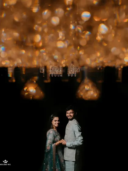An artistic shot of the couple under a sparkling chandelier, creating a beautiful and glamorous portrait.