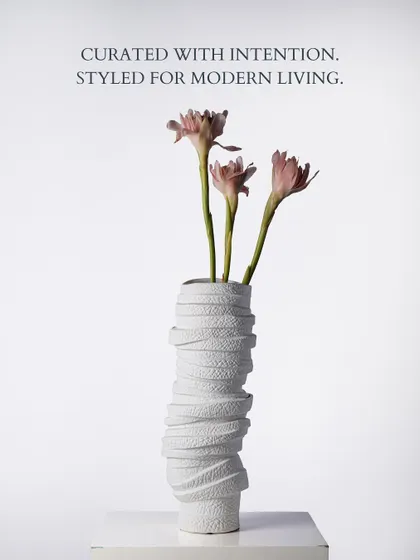 The same wrapped vase, styled with delicate pink florals. This shows how a sculptural piece can serve as a stunning vessel, its texture beautifully complementing the softness of the blooms.