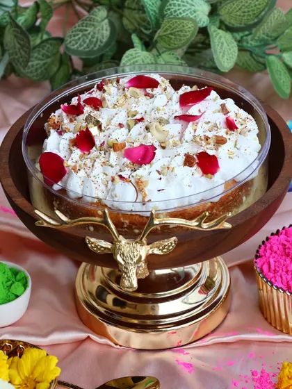 Our Thandai Tres Leches cake, presented in a beautiful serving bowl and topped with rose petals and nuts, ready for a Holi celebration.