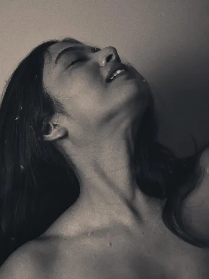 This black and white shot captures a moment of pure ecstasy or release. The tilted head and soft expression are rendered with beautiful, soft grain, giving the image a classic, film-like quality.
