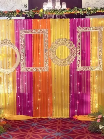 How do you make your mehendi ceremony pop? With a fun and colorful photo booth, of course. We created this backdrop using bright fabric drapes, ornate vintage frames, and delicate fairy lights, giving guests the perfect spot for memorable pictures.