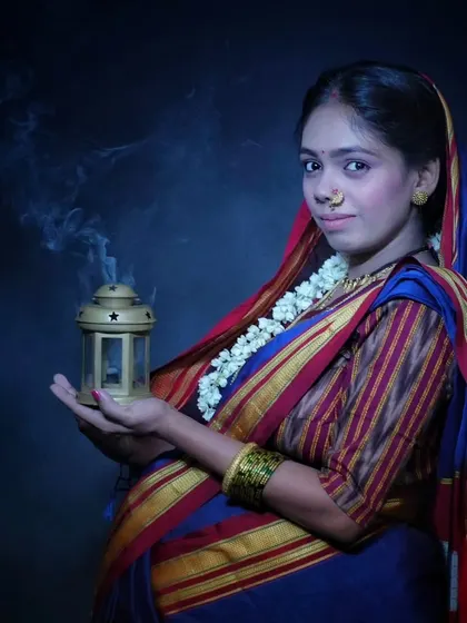 A moody and atmospheric portrait. The traditional Khan saree, the nath, and the gentle smoke from the lantern create a vintage, soulful look that is full of meaning.