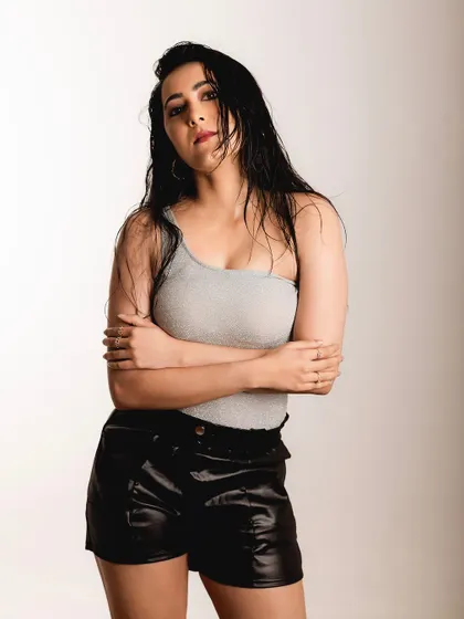A studio portrait with a simple grey top and leather shorts. The lighting is soft but directional, creating a moody and introspective feel.