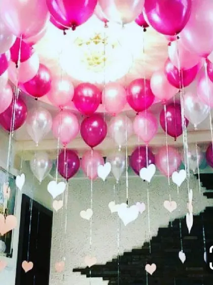 A full ceiling decoration for a welcome baby party. The room is filled with pink, magenta, and white balloons with decorative ribbons and paper hearts hanging down, creating a festive and immersive atmosphere for your celebration.