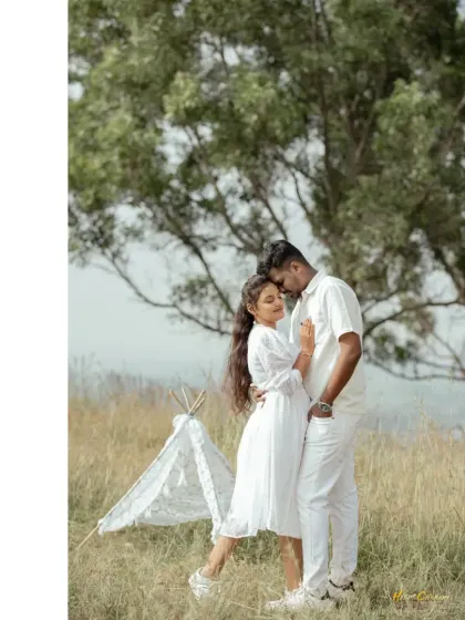 A couple shares an intimate moment in a field, with a small tent prop adding a touch of bohemian charm to their pre-wedding shoot.