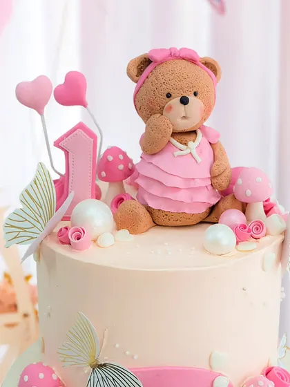 A close-up of the incredibly detailed and cute teddy bear topper, complete with a ruffled dress and tiny necklace.
