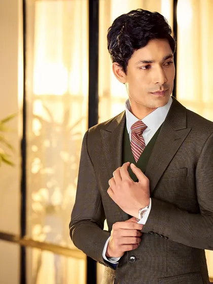We create stunning Italian silhouettes from the finest fabrics. This dark brown three-piece suit is a perfect example of classic tailoring that exudes confidence.