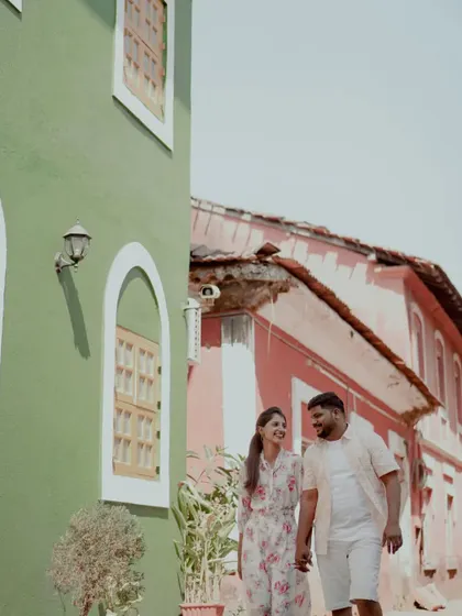Another shot from their Alibag pre-wedding shoot, capturing a candid walking moment against the picturesque buildings.