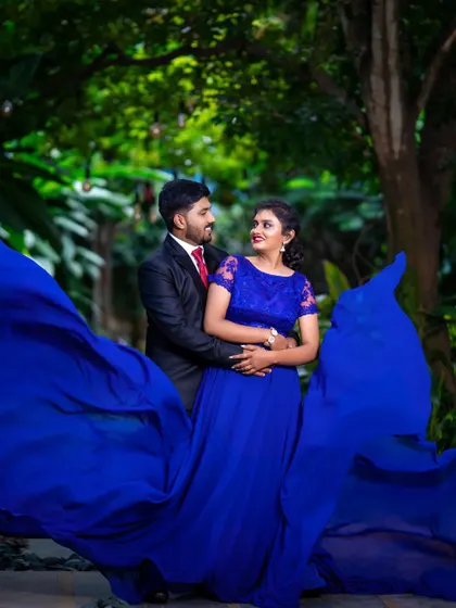 A stunning pre-wedding photo featuring a bride in a royal blue gown with a dramatic, flowing train.