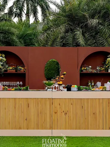 The custom bar was a statement piece, with a bamboo-textured front and a rich terracotta-colored backdrop. It was adorned with magnificent bouquets of yellow and white flowers, creating a stunning focal point.