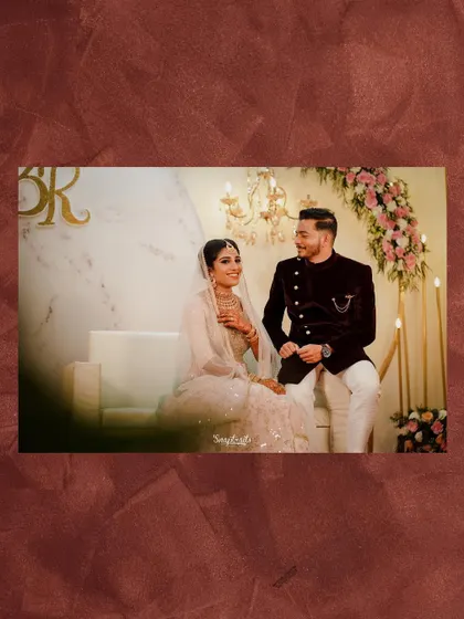 The couple shares a moment on a couch during their reception, surrounded by elegant decor and soft candlelight.