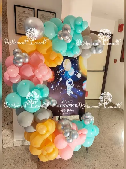 A welcome sign for an astronaut-themed first birthday, framed by a colorful cluster of balloons.
