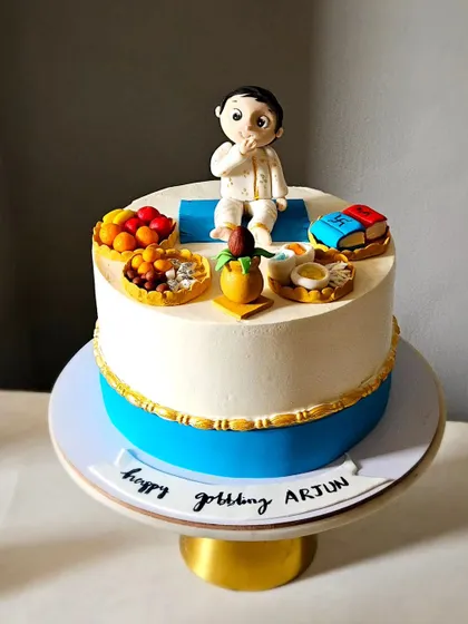 This cake is for an Annaprasan, or a baby's first rice-eating ceremony. It's topped with a handcrafted baby figurine and miniature, edible versions of traditional items used in the ceremony.