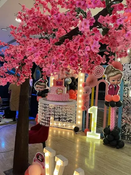 An elegant setup featuring a beautiful cherry blossom tree prop next to a crystal-draped cake table.