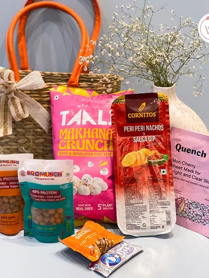 This hamper combines a stylish jute bag with a variety of snacks like makhana and nachos, and even a sheet mask for some post-travel pampering.