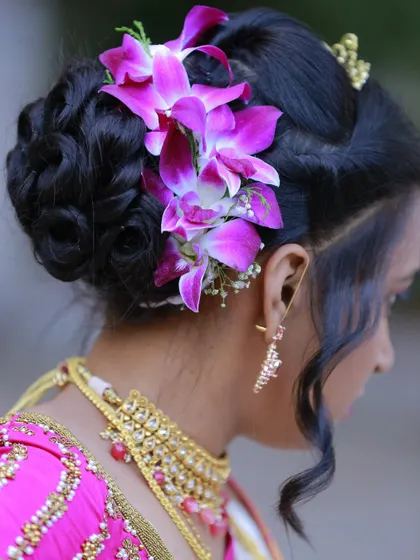 A close-up shot of a bride's elegant hair bun, adorned with beautiful purple orchids.