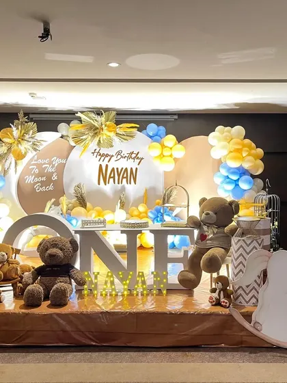 A "Love You To The Moon & Back" first birthday theme with teddy bear props and a soft blue and yellow color scheme.