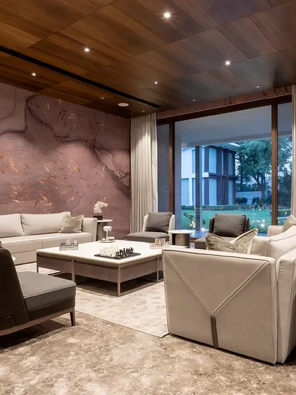 In this farmhouse, the living area is designed to feel open and connected to the outdoors. Neutral-toned furniture is set against a backdrop of custom wallpaper and large windows, creating a serene and light-filled space.