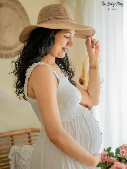 A beautiful solo portrait in our boho setup. The soft, natural light from the window and the stylish hat create a serene and fashionable maternity photo.